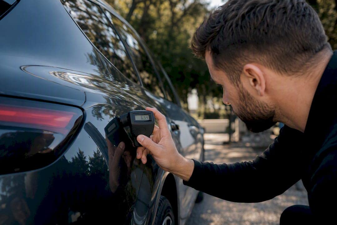 Technician measuring PPF thickness on car fender