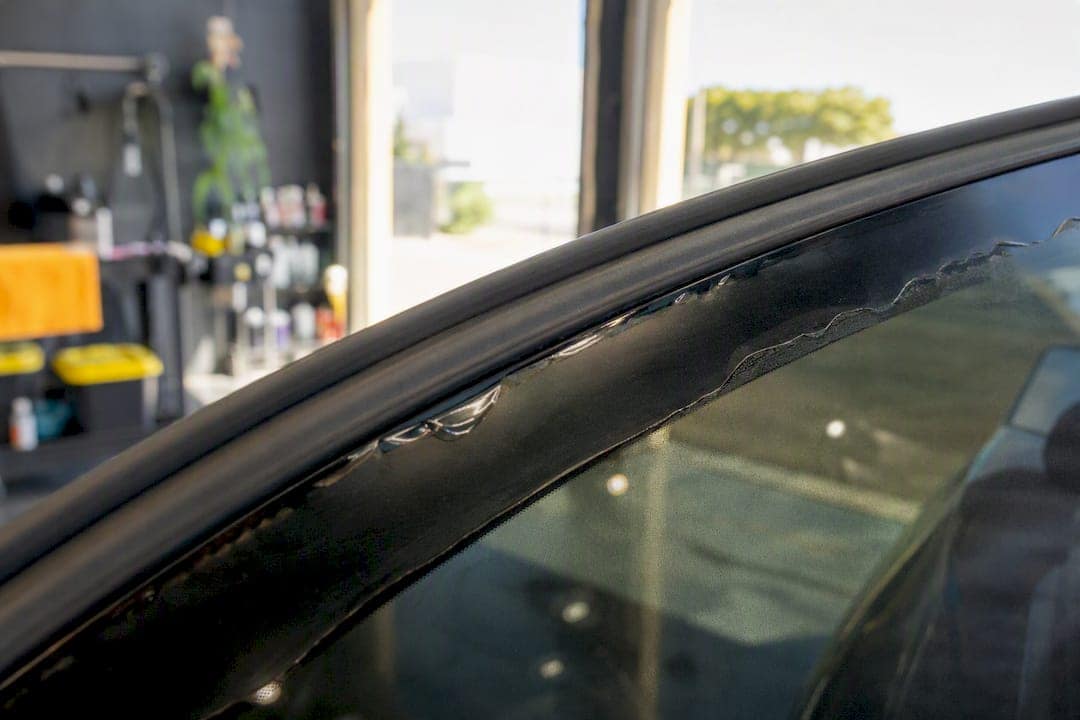 Close-up of peeling window tint on car window edge
