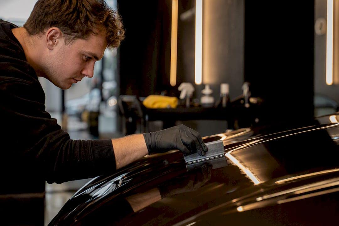 Technician applying ceramic coating on car hood
