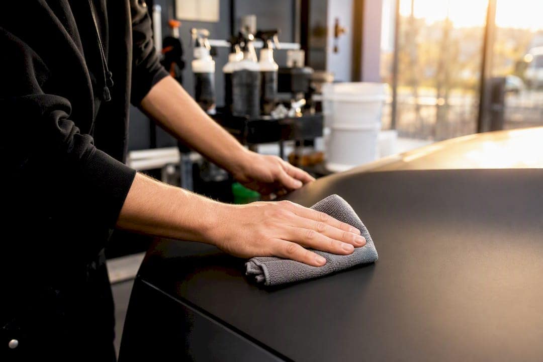 Hands cleaning matte vinyl wrap with microfiber towel