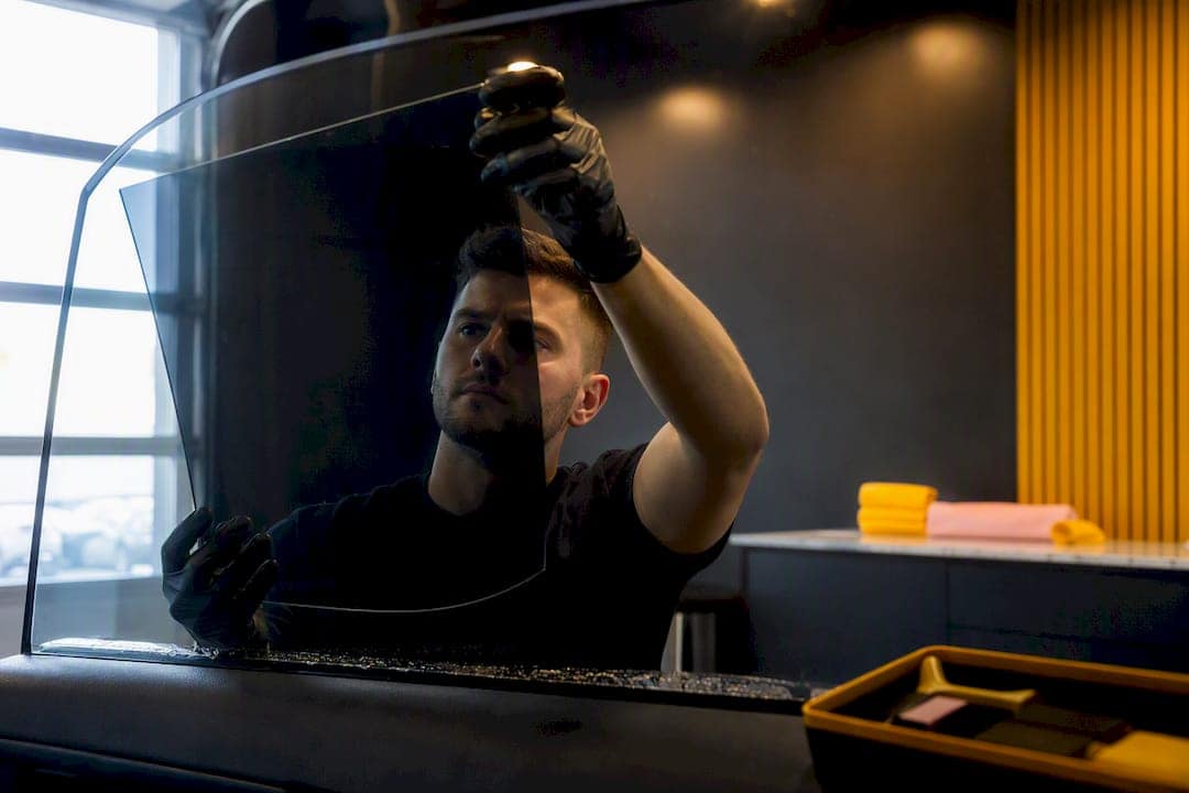 Installer aligning film on tinted vehicle glass