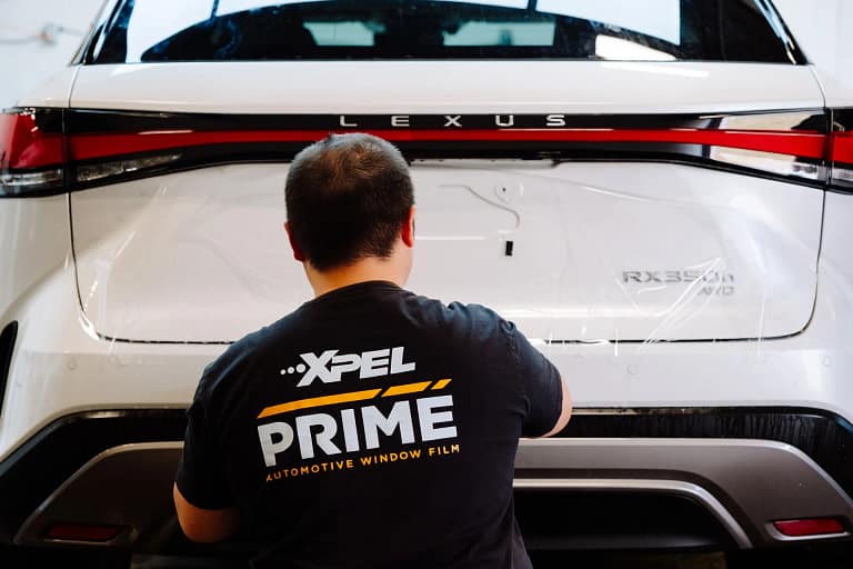 Installer tinting the rear window of a white SUV