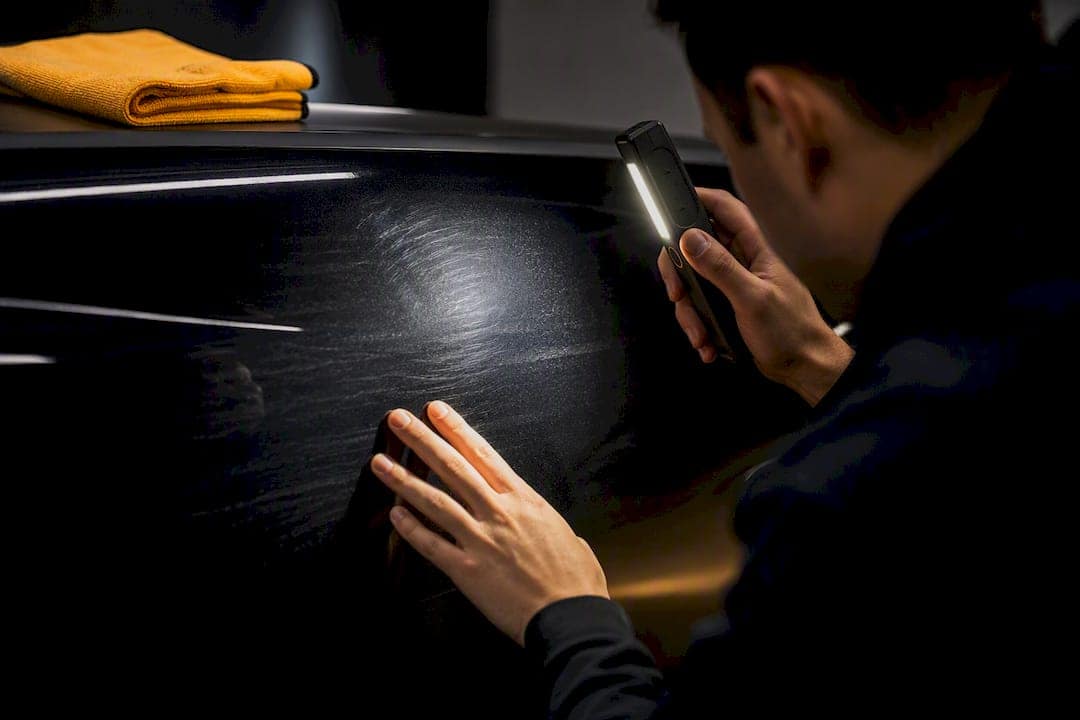 Detailer inspecting paint under swirl-finder light